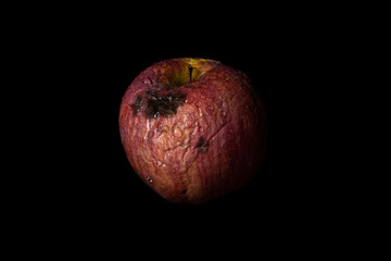Rotten Apple isolated on black background. Concept of decay, aging, sadness and fading away.