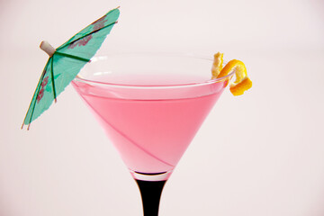 cosmopolitan cocktail in martini glass with lemon peel and green umbrella