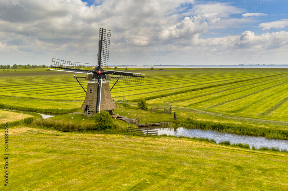 Sticker old wooden windmill in green agricultural grassland