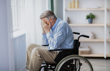 Depression and loneliness in disabled seniors. Elderly man in wheelchair crying near window indoors