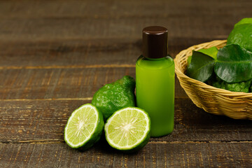Shampoo made of bergamot in green plastic bottle and fresh bergamot fruit and sliced with wicker basket on brown wooden background. Natural products used to care for hair and scalp concept.