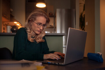 Fototapeta na wymiar one young woman, working late at night at home at desk. typing on her laptop.