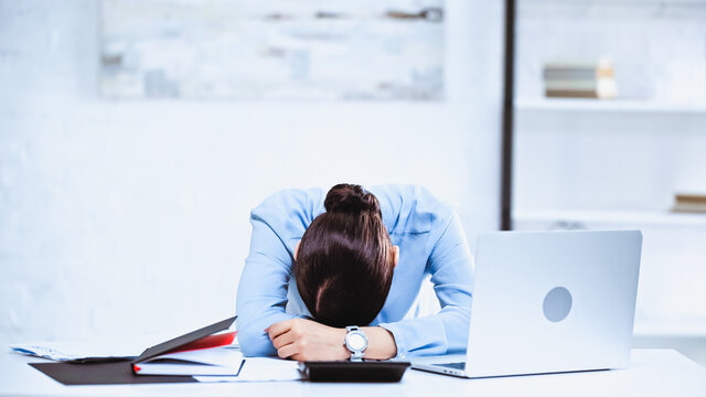 exhausted businesswoman sleeping at workplace in office