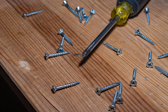 Screwdriver on a wooden top scrounged with screws