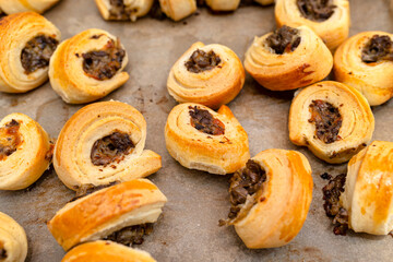 Freshly baked golden patties with mushrooms lying on baking paper.