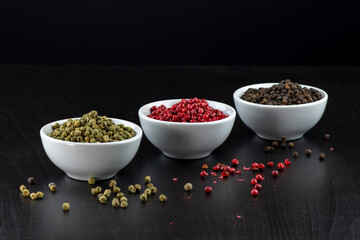 Peppercorns,green,pink and black peppercorns on a black background