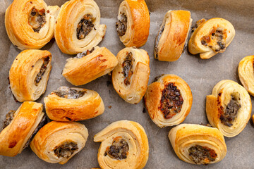 Frozen baked patties in dough on a baking sheet on baking paper, top view.