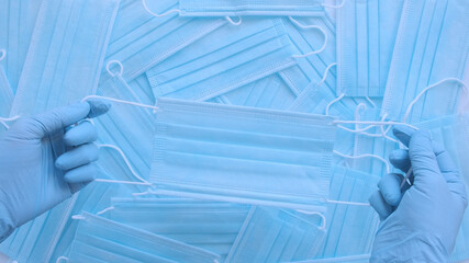 Medical masks. Doctor holds respiratory surgical face mask in hands blue medical gloves on blue background.