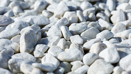 Close-up of light gray pebbles, smooth stones in a wrap-up plan as a background or wallpaper