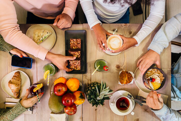 Crop friends around table with tasty food in cafe