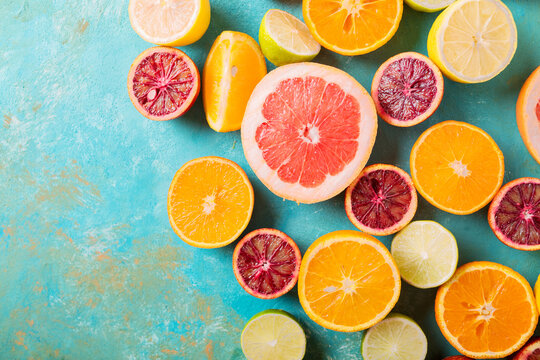 Citrus fruits on turquoise abstract background. &ETH;range, lemon, grapefruit, mandarin, lime. Mixed festive colorful tropical and citrus fruit sliced. Healthy eating photo concept. Copyspace