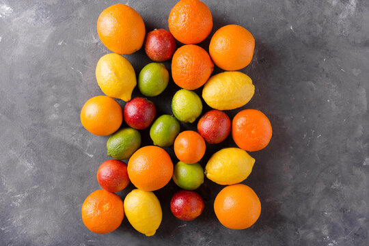 Citrus fruits on gray abstract background. Orange, lemon, grapefruit, mandarin, lime. Mixed festive colorful tropical and citrus fruit. Healthy eating photo concept. Copyspace