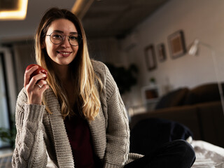 Portrait of a happy pretty girl holding an apple. Young woman having healthy snack.