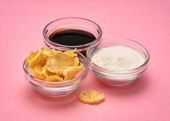 Dried slices of yacon tuber, syrup and powder in small glass bowls against pink paper. Yacon contains inulin, a complex sugar, which promotes healthy probiotics. Superfood concept.