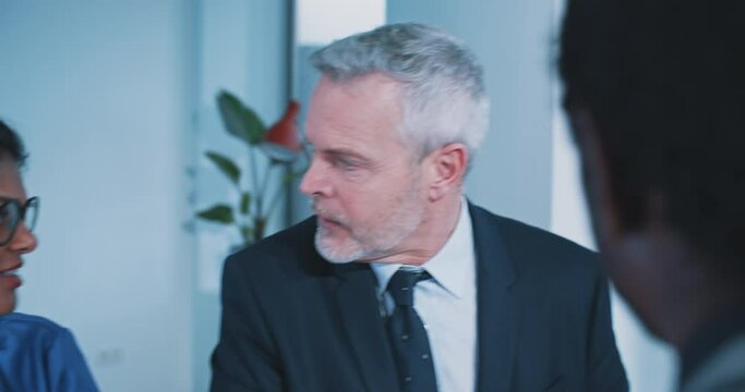 Caucasian businessman with blue eyes intereacting with multi-ethnic colleagues