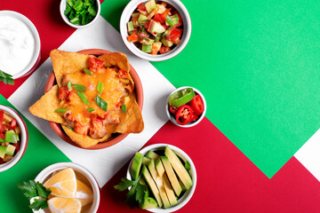 Nachos with chicken, mushroom and melted cheese served with assorted toppings on geometric background. Salsa, avocado, sour cream, lemons, green onion. Copy space. Mexican food