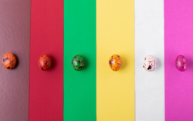 Multicolored quail eggs against the geometric background. Top view. Creative Easter background