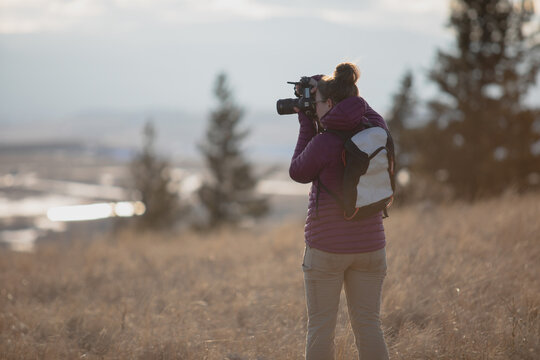 A young woman taking photos in the grasslands on a cold afternoon