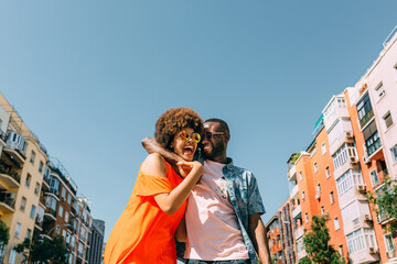 Cheerful black couple hugging on street