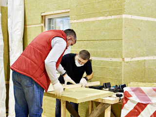 Workers insulate the wall with mineral wool
