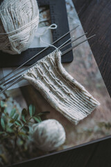 Hand knitting sock with needles and yarn balls ion a dark wooden background.
