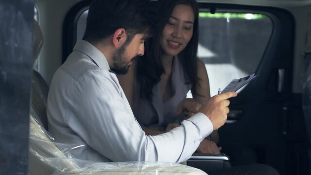 An Asian female car saleswoman explains car information to young male businessmen who come to buy new cars. And consult to help her choose the desired car.    