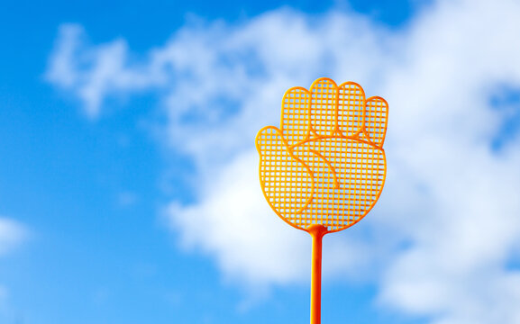 Raise your hand gesture symbol. Yellow plastic fly swatter on blue sky cloud background. Business and Environment concept. Save the World