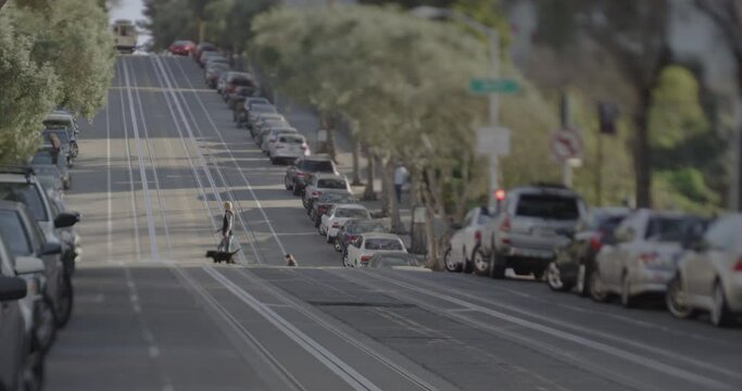 A street on a hill in San Francisco with cable car rails and cars parked at the curbs