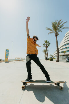 Young man skateboarding with a longboard in front of the beach