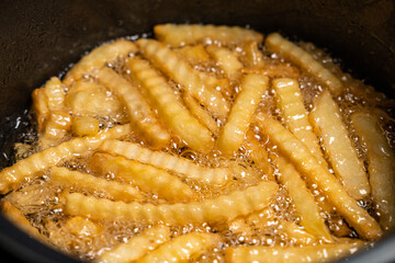 French fried potatoes frying in boiling oil
