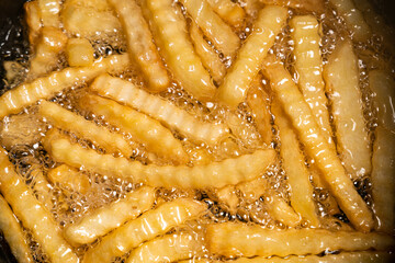 French fries in a deep fryer closeup - obrazy, fototapety, plakaty