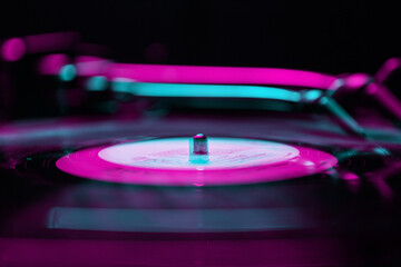 Listen to music from vinyl record disc with retro turn table player device. Professional dj audio equipment in neon lights on stage in night club. Platter disc with analog vinyl disc with music