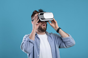 Cool millennial guy experiencing virtual reality in VR headset on blue studio background