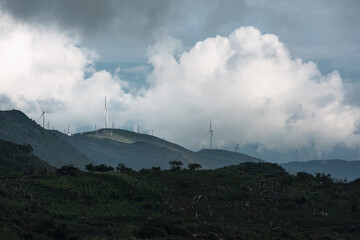 Fototapeta na wymiar Wind turbines in the clouds on top of the mountain