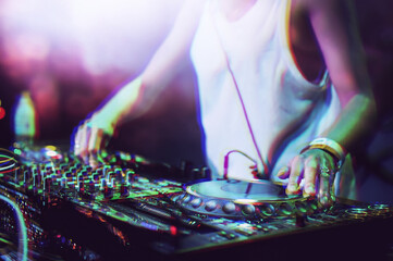 Girl dj playing music on concert stage in night club. Professional female disc jockey plays musical...