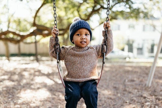 An adorable little boy on a park swing
