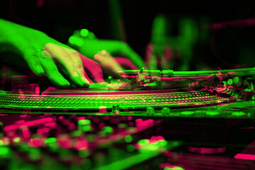 Hip hop dj scratching vinyl record with turntable needle on rave party in night club in bright...