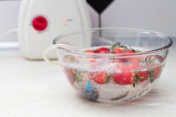 strawberry in a bowl with water with a round ozonating stone. Tubes leading to oxygen pump and ozone generator. ozonation fruit. Food disinfection with ozon.