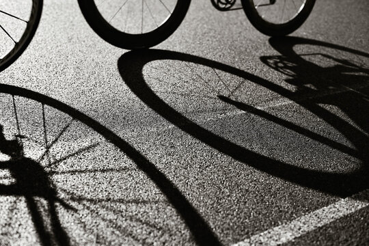 Road Cycling Racing Bike Abstract backlit view of shadow bicycle wheel racing along road in bicycle lane. Silhouette of front and rear road bike on a bright modern pavement