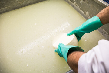 Crop man washing cheese in brine
