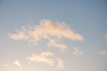 Morning clouds in sky highlighted by sunshine of the whispy white clouds floating against blue sky...