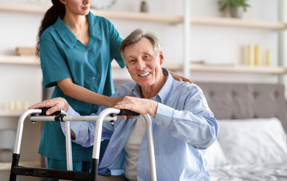 Disabled Senior Man Receiving Medical Assistance From Young Caregiver At Home, Copy Space