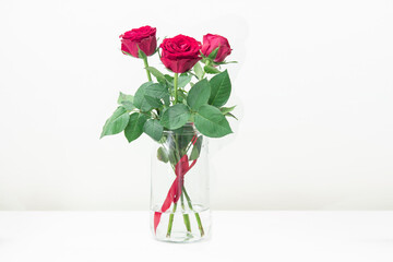 Bouquet of red roses in a glass bottle placed on a wooden table. Wedding decorations, Valentine's day, home decorations Or office. Doing export business of flowers. copy space