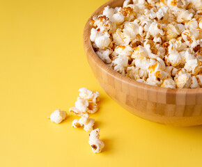 Popcorn in a wooden bowl on a bright yellow background. selective sharpness