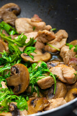 turkey meat with mushrooms and rocket in frying pan