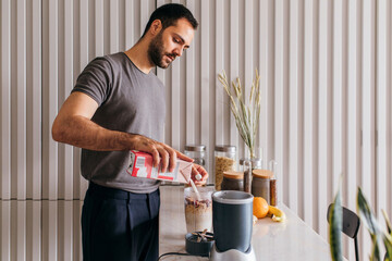 Young man making smoothie in the kitchen