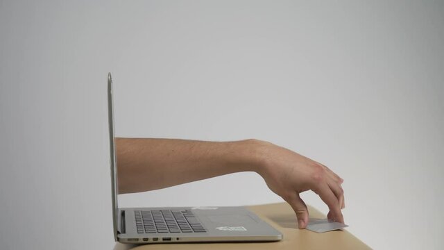 The abstract image of the hackers hand reach through a laptop screen for stealing credit card in a wallet. the concept of cyber attack, virus, malware, illegally and cyber security.