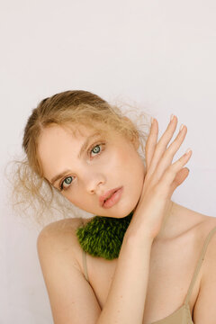 Sensual portrait of a young blond girl with a fluffy flower on the neck