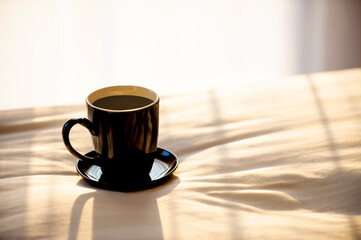morning a cup of coffee on bed. The light of the rising sun came through the window.