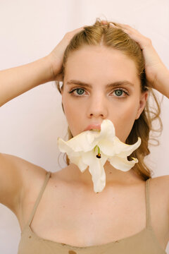 Sensual portrait of a young ginger head girl with a lily flower in her mouth